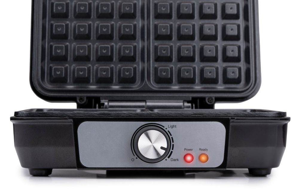 Otwarta gofrownica marki Alpina, widziana do połowy. Na pierwszym planie jest pokrętło i dwie lampki.